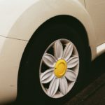 White car wheel with a yellow daisy hubcap